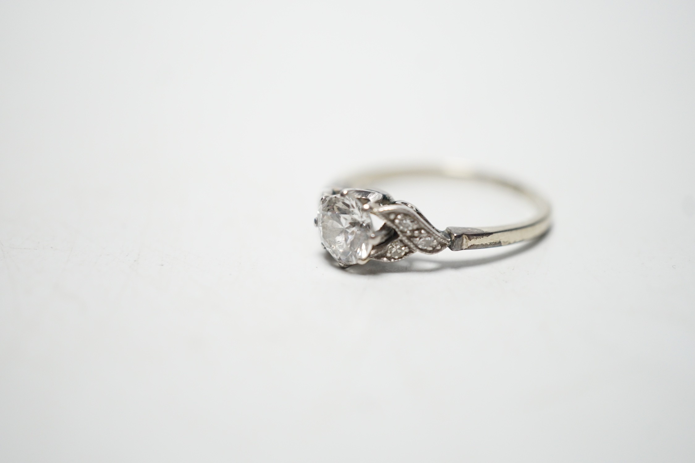 An 18ct white metal and single stone diamond ring, with diamond chip set shoulders, the stone weighing approximately 0.60ct, size M, gross weight 1.8 grams.